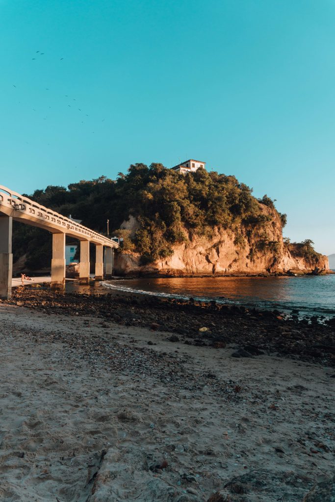 beach-surrounded-by-sea-rocks-covered-greenery-with-bridge-brazil~1 (1)